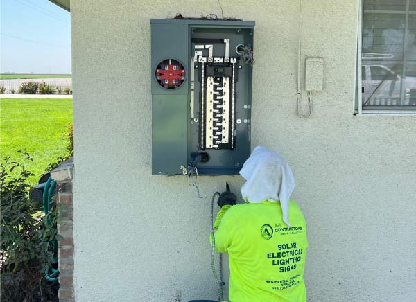 An A-1 Contractors residential electrician carefully inspecting a main electrical panel for any signs of failure or damage.