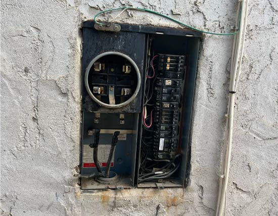 An old, corroded electrical panel with rust on the metal, indicating it is likely an outdated system that needs replacement.