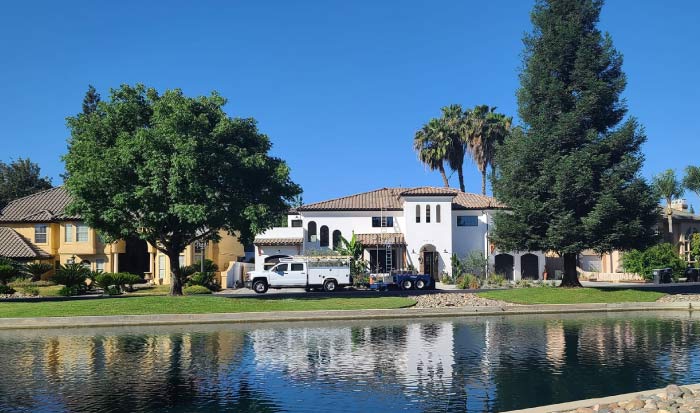 Wide exterior view of a large, custom-style home next to a waterway, with an A-1 Contractors service truck parked outside, illustrating a major project by general contractors