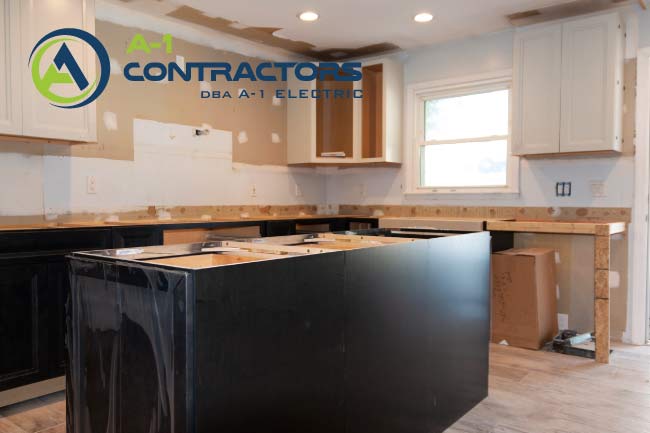 Construction phase of a central kitchen island with black shaker cabinetry and unfinished drywall during a major home kitchen overhaul