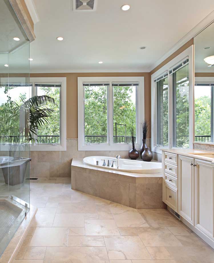 Completed luxury master bathroom remodel featuring a corner soaking tub, glass shower enclosure, beige tile flooring, and custom vanity lighting